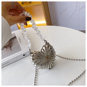 Detail of silver heart-shaped metal mini box bag with clear beaded handle and chain strap