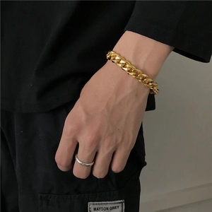 Polished 18K gold Cuban link chain bracelet and minimalist silver ring on male model