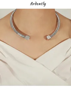 Détail du collier rigide en acier argenté avec des pendentifs carrés sertis de cristaux