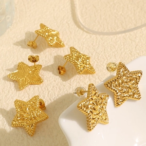 Set of six gold star earrings with pleated texture finish on a ceramic tray