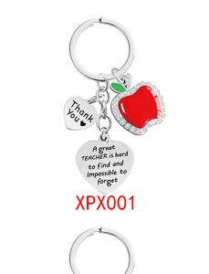 Macro shot of silver metal keychain with enamel red apple charm and thank you heart pendant