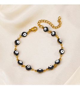 Detail of gold evil eye bracelet with black enamel charms and lobster clasp on silk