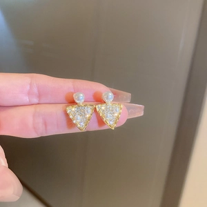 Detail of gold triangle earrings featuring inlaid pearls and shimmering pavé zircons