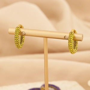 Detail of C-shaped gold-plated hoop earrings with pave-set lime yellow crystals