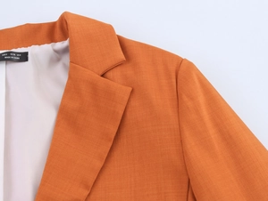 Detailed close-up of orange blazer collar and shoulder with high-quality fabric texture