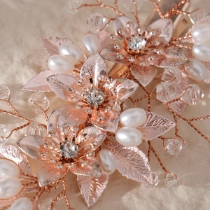 Macro detail of rose gold flower hair comb with crystal beads and white faux pearls