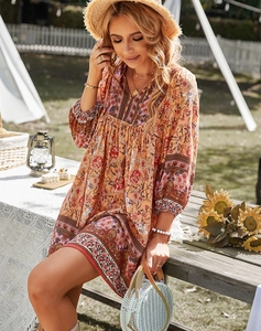 Détail d'une robe bohème orange à fleurs avec col en V et manches cloches en plein air