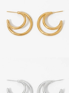 Flat lay of double-layered C-shaped gold and silver hoop earrings on a white background