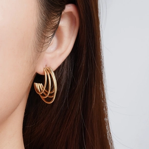 Close-up of layered 18K gold-plated stainless steel earrings worn by a model