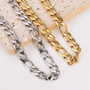 Classic gold and silver 11mm Figaro chains displayed on a textured stone surface