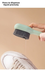 Detail view of liquid-dispensing shoe brush cleaning a white leather sneaker