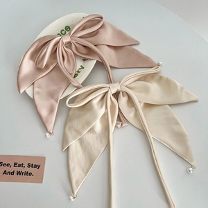 Detail of satin bow hair clips with hanging pearl charms in pink and cream silk