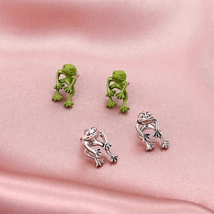 Vintage metal frog stud earrings in green enamel and antique silver finish on pink silk