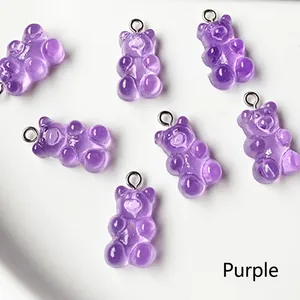 Macro detail of seven purple resin gummy bear charms with silver metal rings on a tray