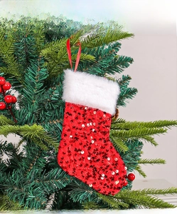Detail of red sequined Christmas stocking hanging on tree with white faux fur trim