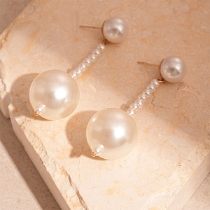 Detail of vintage double pearl drop earrings with gold beads on stone display