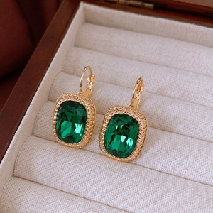 Macro detail of vintage emerald square earrings with gold milgrain edges in velvet box