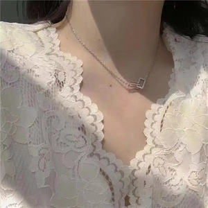 Close-up of interlocking geometric silver pendant with crystals on a delicate chain