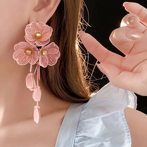 Détail d'une boucle d'oreille fleur rose avec zircon et gland en forme de goutte d'eau