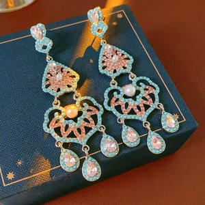 Détail macro de boucles d'oreilles vintage avec pierres turquoise et roses et pompon