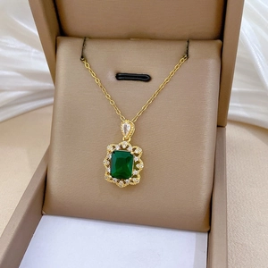 Gros plan d'un collier doré avec une pierre verte rectangulaire et de petits cristaux