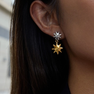 Detailed view of two-tone sun-shaped drop earrings in polished silver and gold finish