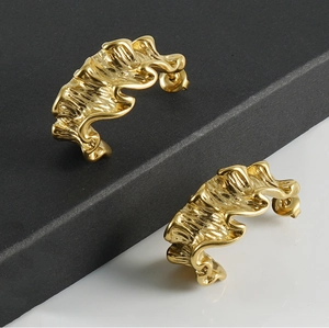 Macro detail of 18K gold-plated stainless steel earrings with irregular lava ripple texture