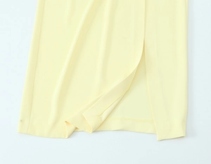 Close-up of light yellow pleated midi dress showing hem stitching and side slit detail