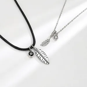 Detail of silver feather pendant necklaces with black cord and crystal accents