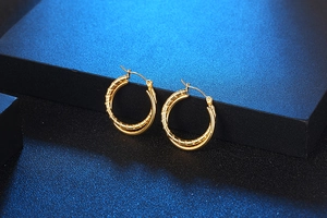 Detail of gold double hoop earrings with textured wavy design and polished finish