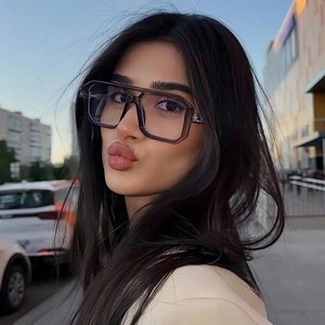 Close-up of double-bridge pilot eyewear featuring transparent grey frames on a model