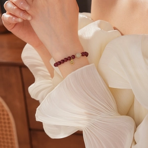 Model wearing a Hetian jade and cinnabar gourd bracelet with a gold Fu pendant charm