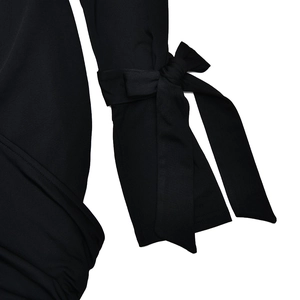 Detailed view of the black knit dress sleeve featuring a self-tie decorative fabric bow