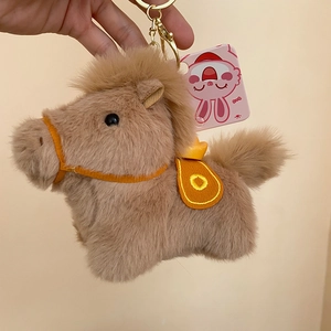 Dettaglio ciondolo pony in peluche con sella arancione e portachiavi dorato