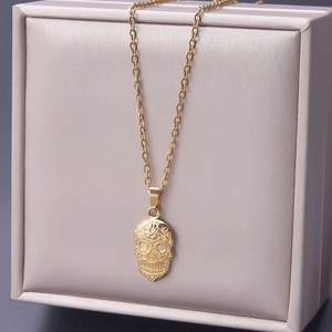 Detailed close-up of 18k gold-plated skull pendant with intricate rose engravings on a chain
