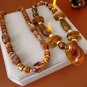 Vintage amber resin beaded necklace with gold metal spacers on a grey velvet display