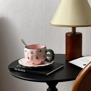 Detail of pink floral ceramic cup with dark green handle on a black side table