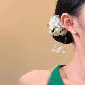Close-up of elegant fabric flower hair clip with tassels and pearls on model