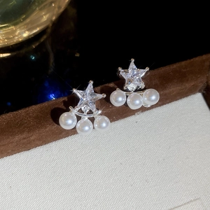 Dettaglio ravvicinato di orecchini a stella in zircone con tre perle bianche su perno argento