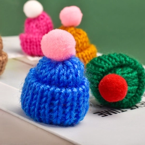 Close-up of colorful mini knitted hats with pom-poms for bottles and crafts