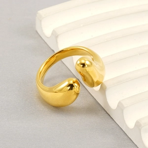 Detailed top view of a chunky gold teardrop ring on a white corrugated textured surface