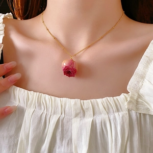 Detail of a preserved rose necklace in gold with a gradient pink petal pendant
