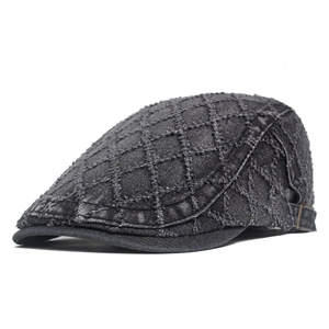 Macro detail of dark grey denim flat cap showing quilted texture and metal side buckle