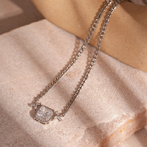 Close-up of silver Cuban chain necklace with an octagonal zircon pendant on stone background