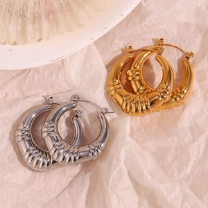 Detailed close-up of chunky gold and silver spiral textured hoop earrings on art paper