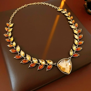 Détail d'un collier vintage avec feuilles dorées et pendentif en cristal ambré