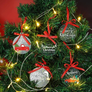 Clear acrylic Christmas ornaments with red ribbons hanging on a decorated tree