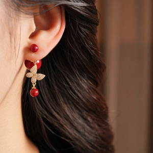Macro detail of red butterfly pearl earrings with gold plating and zircon inlay for women