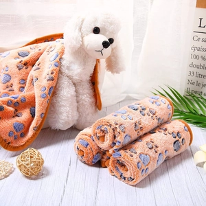 Soft orange coral fleece pet blanket featuring colorful paw prints and plush textures