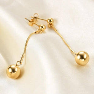 Macro shot of 18K gold 10mm ball drop earrings with snake chain on silk background